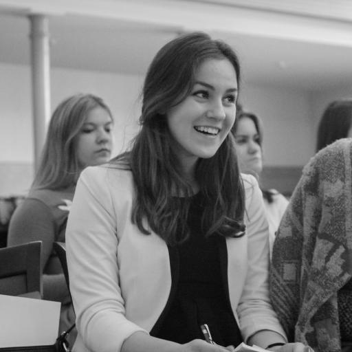 Elizabeth Lasmane - A white girl in a white jacket in a lecture room with other people. 